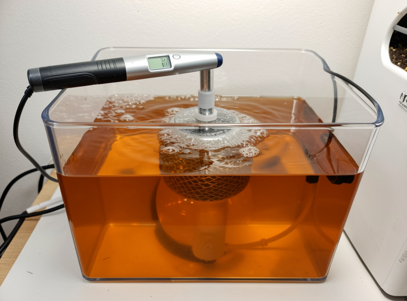 A clean clear hydroponic reservoir with an air stone bubbling and a pH pen reading in the 5.5 to 6.0 range