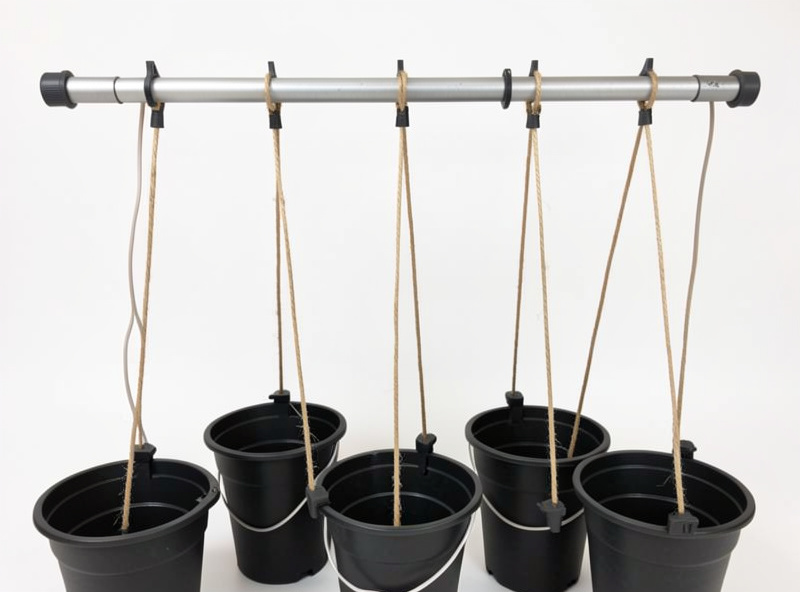 Overhead support bar with twine strings dropping to hydroponic buckets and printed string anchors